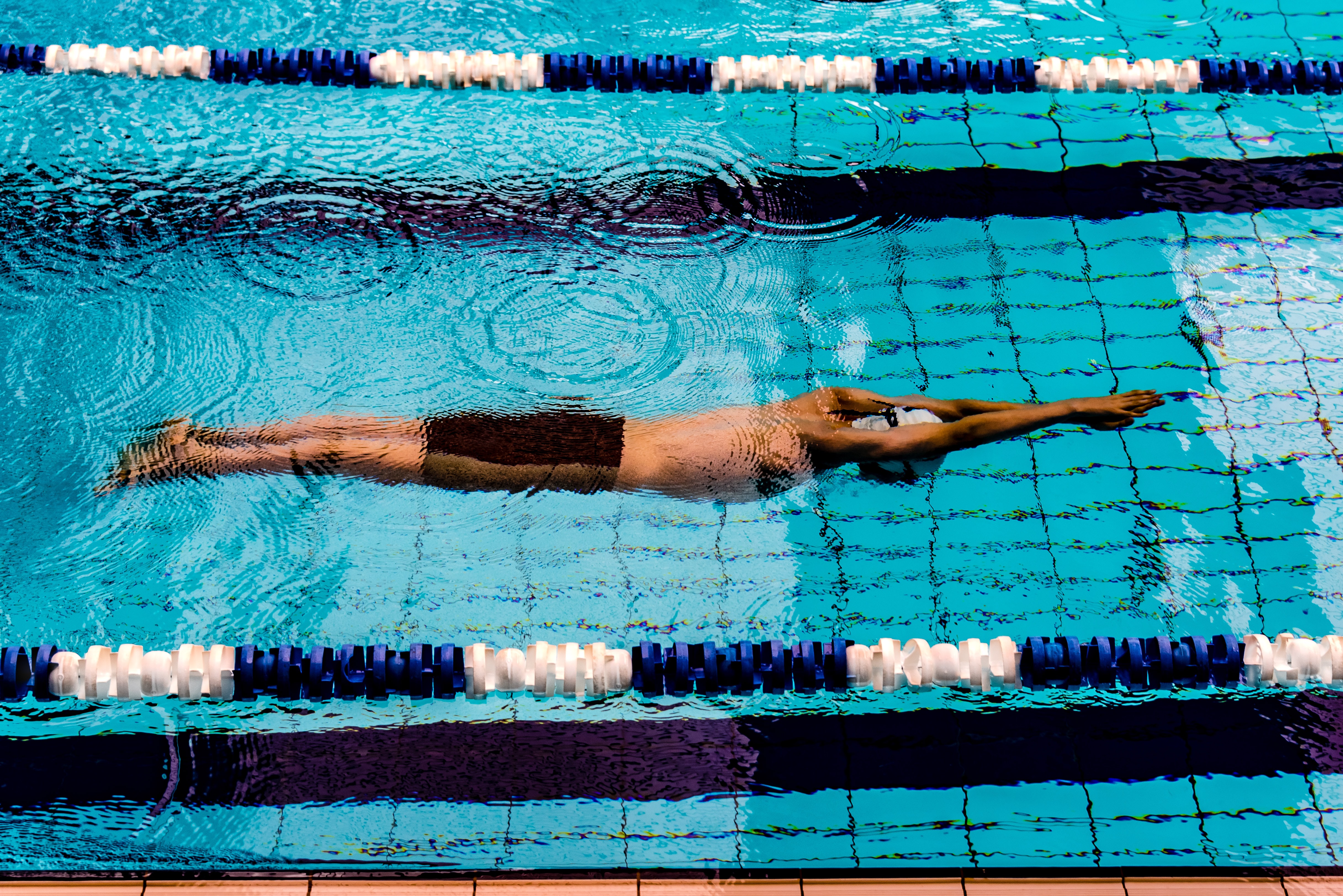 Hombre nadando en pista de piscina 