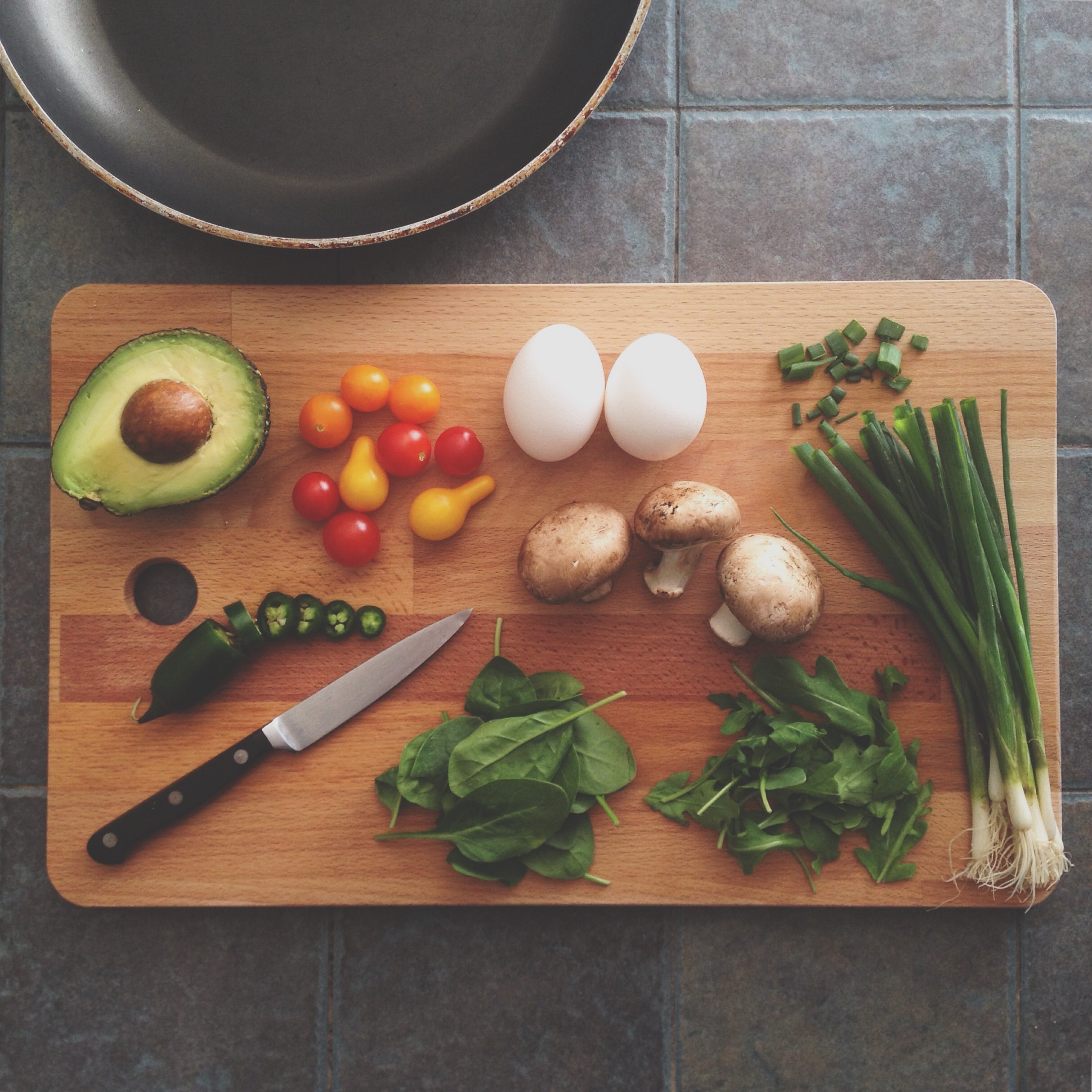 Tabla de cortar con verduras, huevo y un cuchillo 