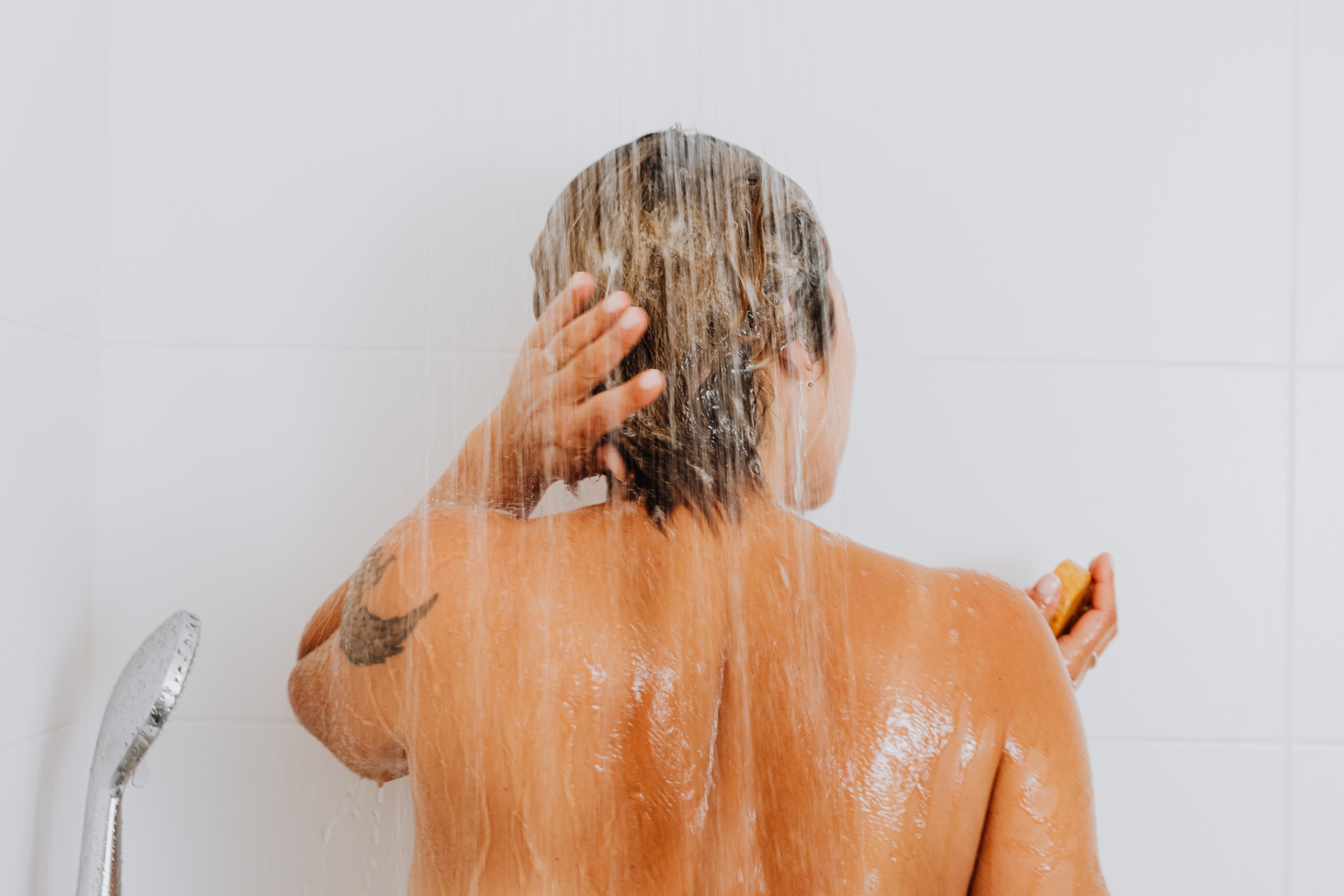 Persona de espalda a la cámara dandose una ducha