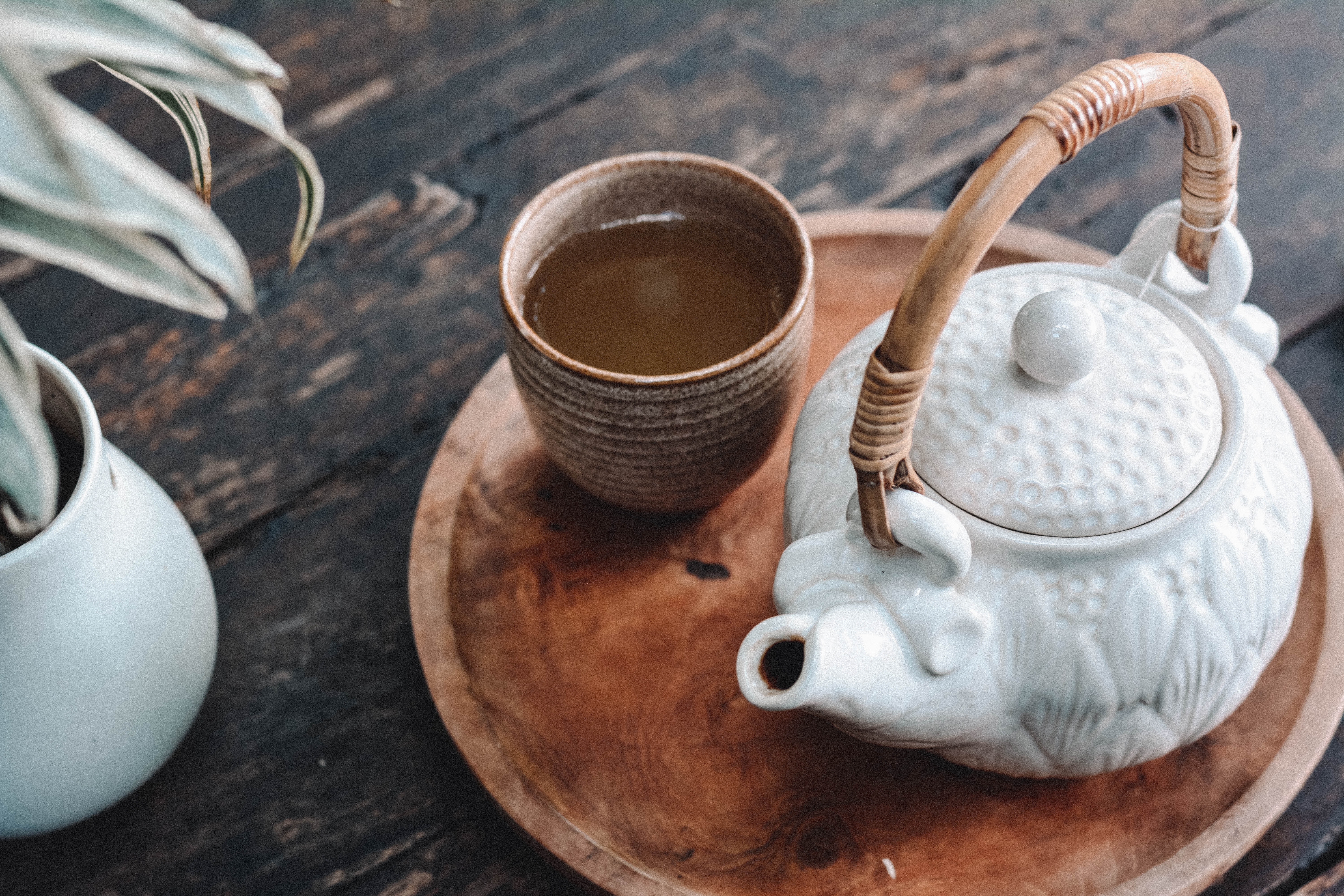 Tetera y taza con té, sobre una pequeña tabla de madera