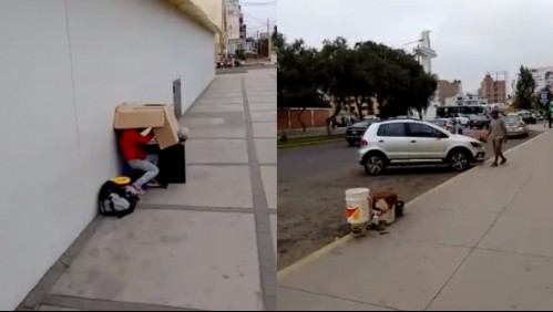 Niña estudia debajo de una caja de cartón mientras su padre limpia autos para conseguir dinero