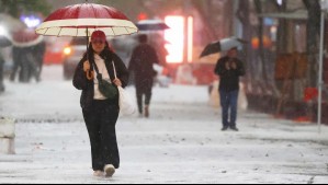 Personas caminando con lluvia en Santiago