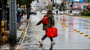 Imagen de una mujer cruzando la calle durante la lluvia en Santiago.