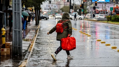 Imagen de una mujer cruzando la calle durante la lluvia en Santiago.